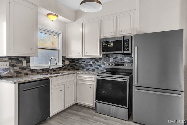 kitchen featuring light stone countertops, appliances with stainless steel finishes, sink, light hardwood / wood-style flooring, and white cabinets