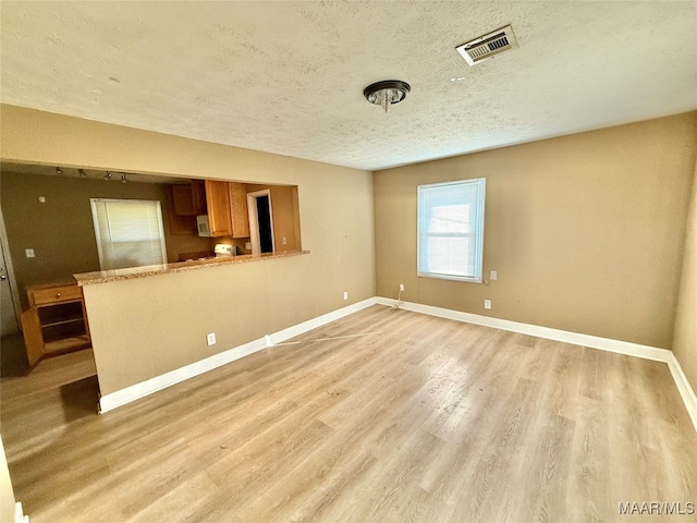 spare room with light hardwood / wood-style floors and a textured ceiling