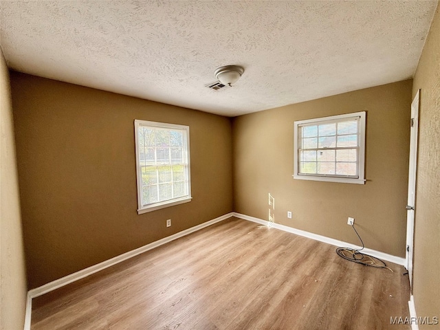 empty room featuring a textured ceiling and light hardwood / wood-style flooring