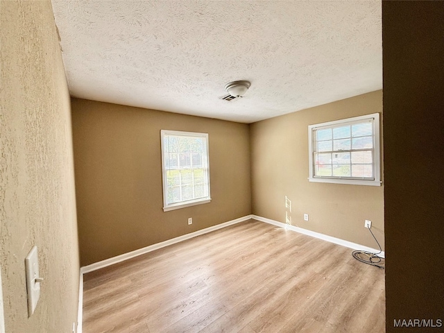 spare room with light hardwood / wood-style flooring and a textured ceiling