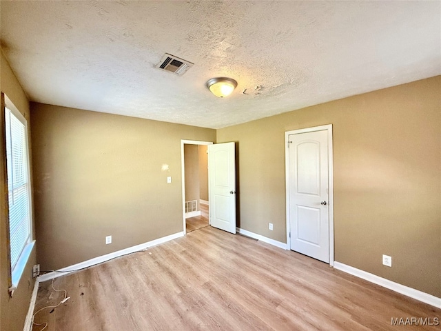 unfurnished bedroom featuring a textured ceiling and light hardwood / wood-style flooring