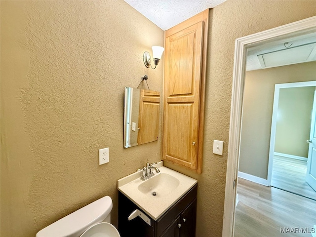 bathroom with hardwood / wood-style flooring, vanity, toilet, and a textured ceiling