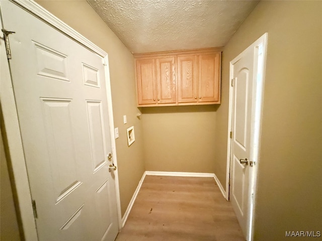 washroom with hookup for a washing machine, cabinets, a textured ceiling, and light wood-type flooring