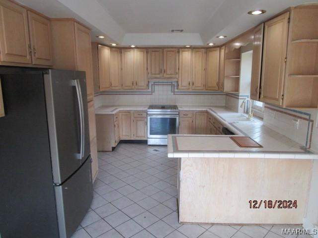 kitchen featuring sink, light brown cabinets, backsplash, kitchen peninsula, and appliances with stainless steel finishes