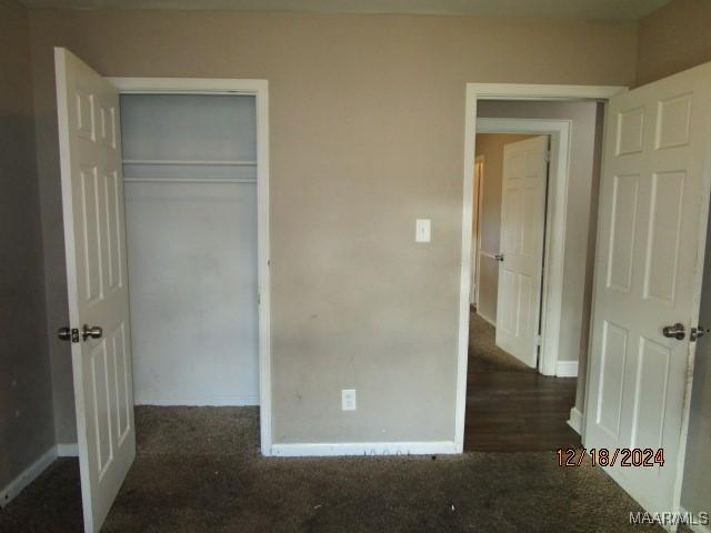 unfurnished bedroom with dark hardwood / wood-style floors and a closet