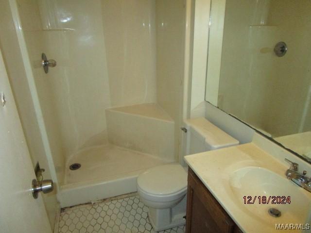 bathroom featuring toilet, a shower, and vanity