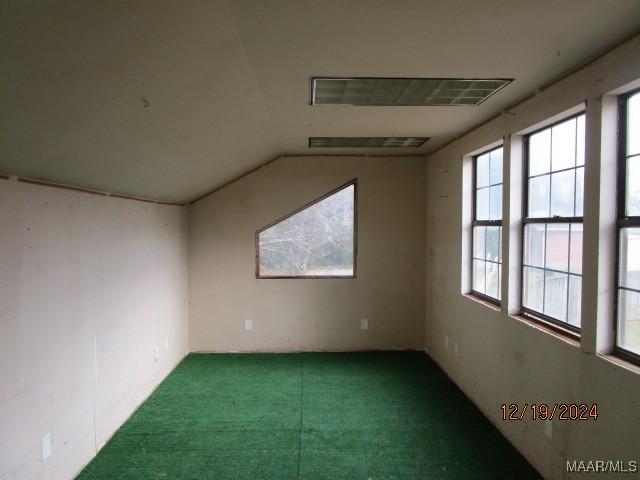 unfurnished room featuring plenty of natural light and lofted ceiling