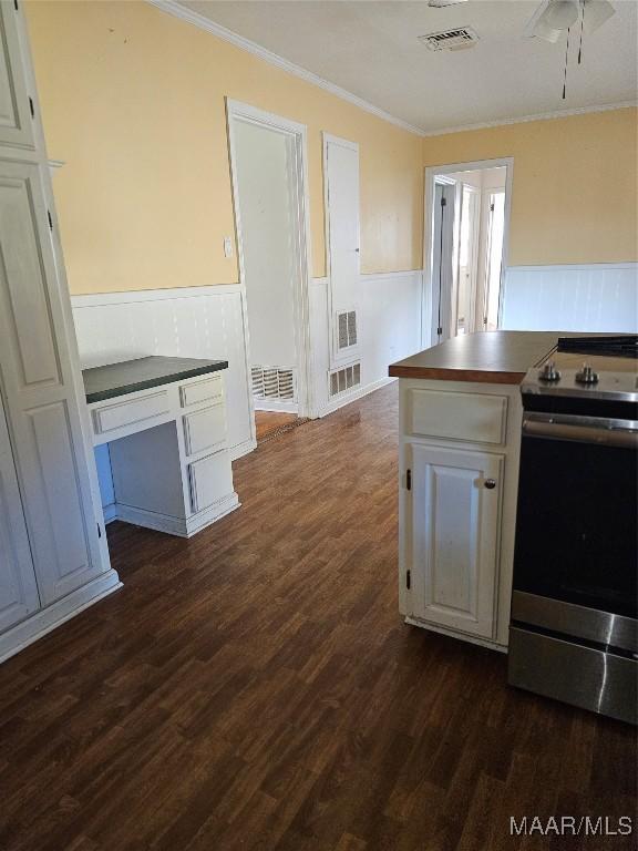 kitchen with dark hardwood / wood-style floors, stainless steel electric stove, white cabinetry, ornamental molding, and ceiling fan