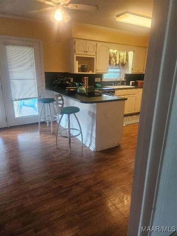 kitchen with sink, kitchen peninsula, white cabinets, and a breakfast bar area