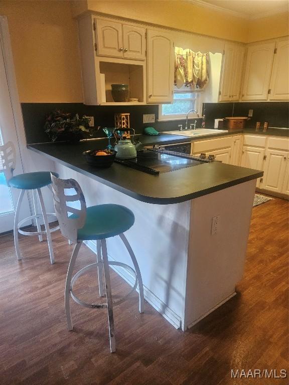 kitchen featuring a kitchen breakfast bar, white cabinetry, dark hardwood / wood-style floors, and kitchen peninsula