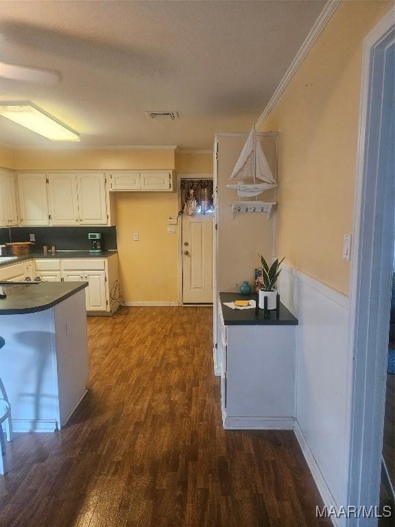 kitchen with dark hardwood / wood-style flooring, white cabinetry, and crown molding