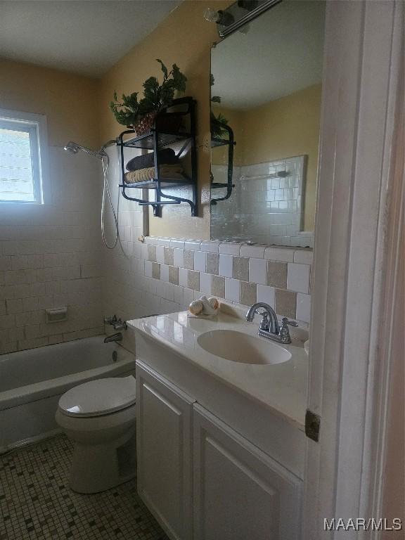 full bathroom with tiled shower / bath combo, toilet, vanity, tile patterned floors, and backsplash