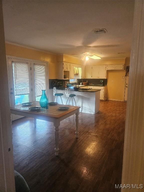 kitchen with white cabinets, dark hardwood / wood-style flooring, kitchen peninsula, and ceiling fan