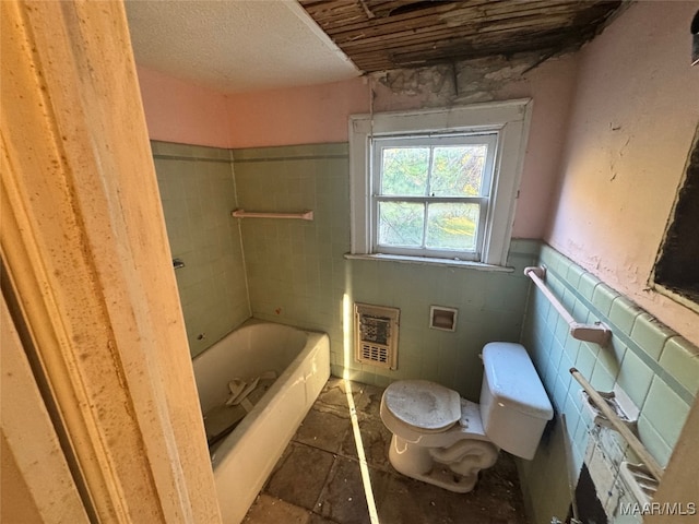 bathroom featuring toilet, a tub to relax in, and tile walls