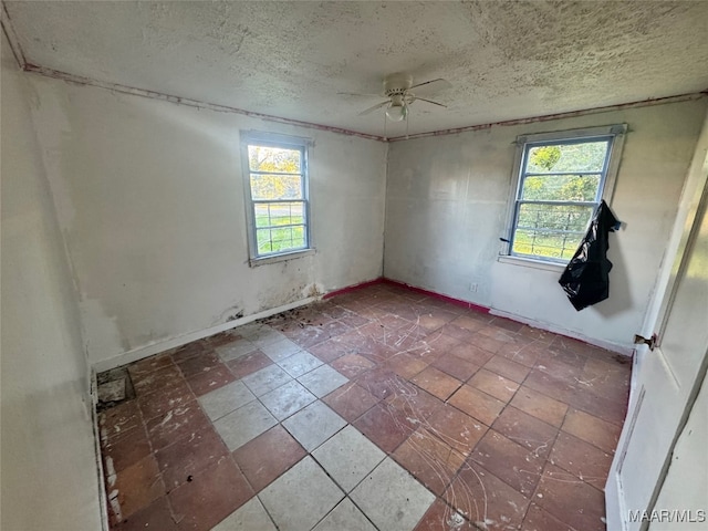 spare room featuring a wealth of natural light, ceiling fan, and a textured ceiling