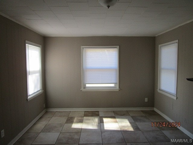 tiled empty room featuring crown molding