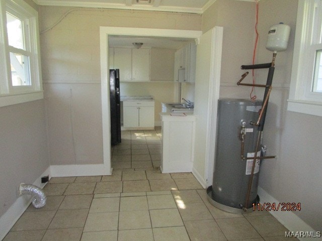 washroom featuring light tile patterned floors, sink, a healthy amount of sunlight, and water heater