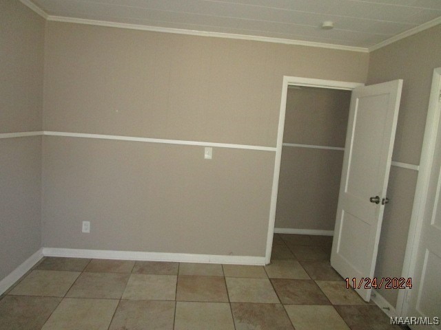 spare room with tile patterned flooring and crown molding