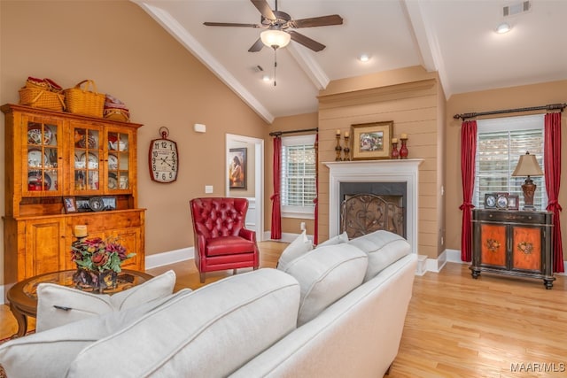 living room featuring a fireplace, vaulted ceiling with beams, light hardwood / wood-style floors, and a healthy amount of sunlight