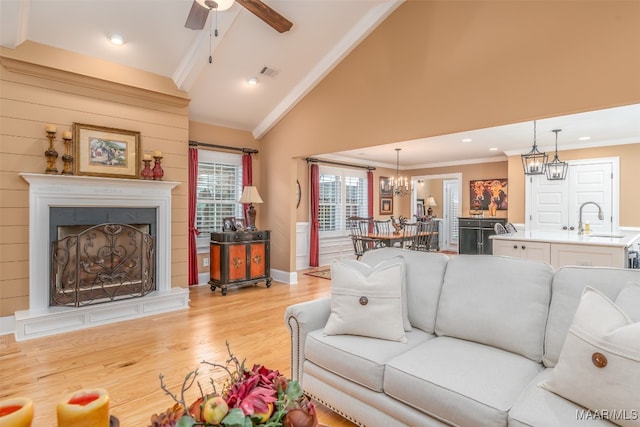 living room featuring crown molding, sink, ceiling fan, and light wood-type flooring