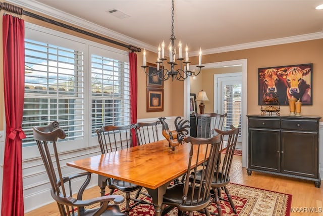 dining room with crown molding, a chandelier, and light wood-type flooring