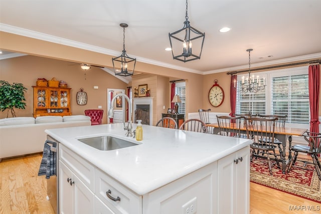 kitchen featuring white cabinets, a center island with sink, hanging light fixtures, and sink