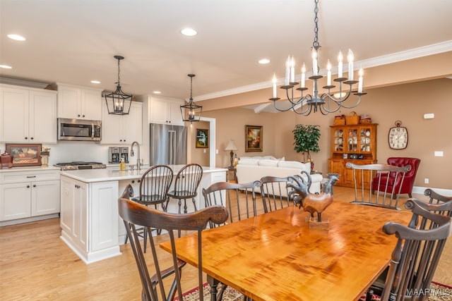 dining space featuring sink, light hardwood / wood-style flooring, a chandelier, and ornamental molding