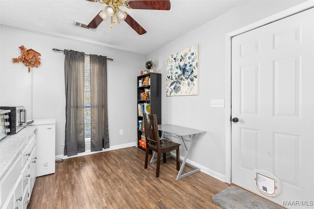 office area featuring baseboards, visible vents, a ceiling fan, wood finished floors, and a textured ceiling