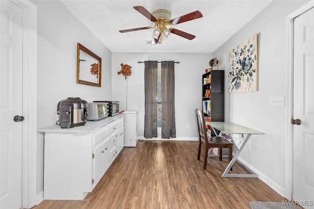 office area featuring baseboards, a textured ceiling, a ceiling fan, and wood finished floors