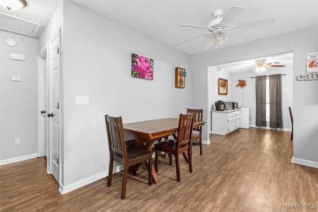 dining area featuring attic access, baseboards, ceiling fan, wood finished floors, and a textured ceiling