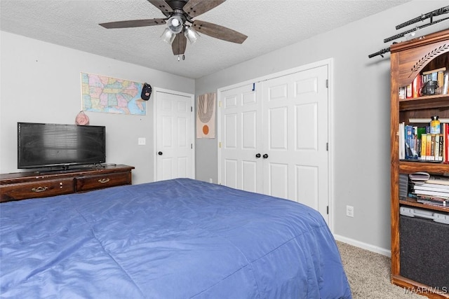 carpeted bedroom with ceiling fan, a closet, baseboards, and a textured ceiling