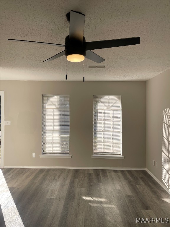 unfurnished room with ceiling fan, dark wood-type flooring, and a textured ceiling