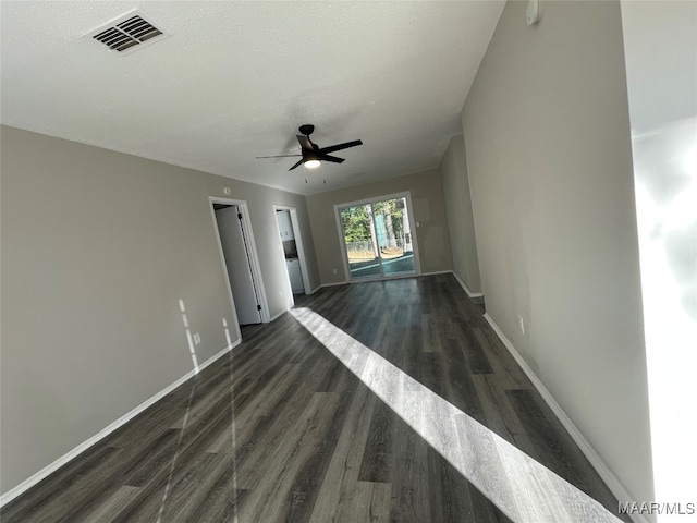 empty room featuring a textured ceiling, ceiling fan, and dark wood-type flooring