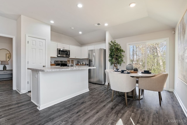 kitchen featuring stainless steel appliances, dark hardwood / wood-style floors, an island with sink, vaulted ceiling, and white cabinets