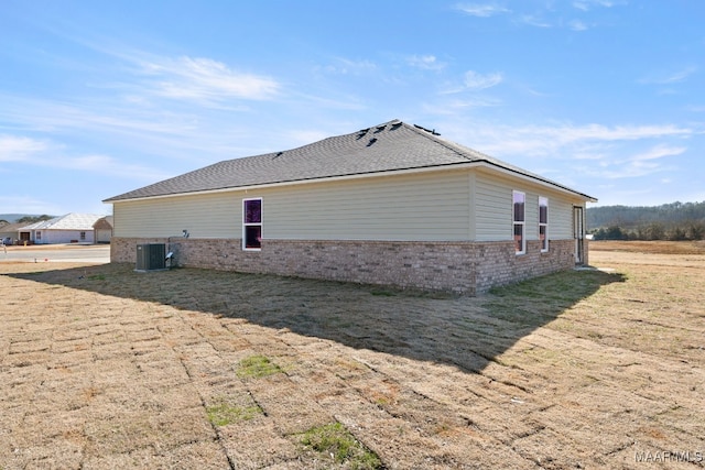 view of side of home with central AC unit and a yard