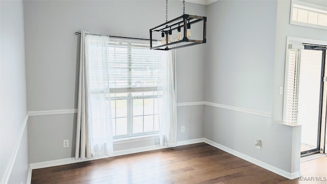 unfurnished dining area with dark hardwood / wood-style floors and an inviting chandelier