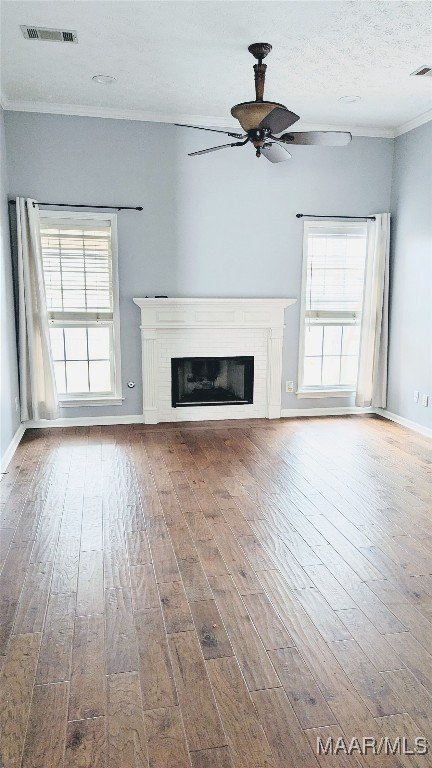 unfurnished living room with ceiling fan, wood-type flooring, a textured ceiling, and ornamental molding