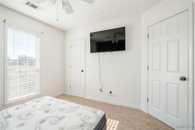 carpeted bedroom with ceiling fan and a textured ceiling