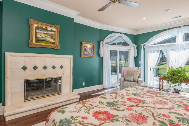 bedroom with a tile fireplace, ceiling fan, access to exterior, ornamental molding, and wood-type flooring