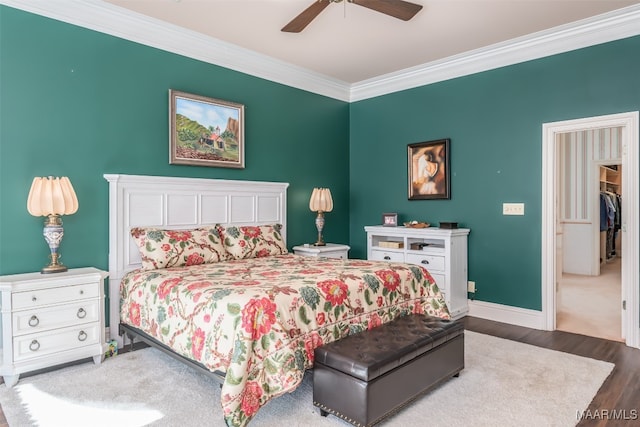 bedroom featuring hardwood / wood-style floors, ceiling fan, a spacious closet, ornamental molding, and a closet