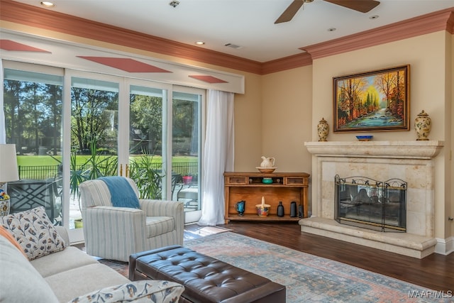 living room featuring crown molding, dark hardwood / wood-style flooring, ceiling fan, and a premium fireplace