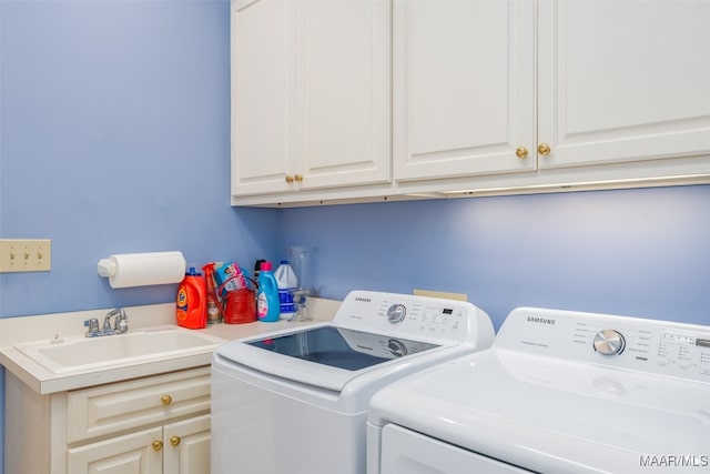 clothes washing area featuring cabinets, washing machine and dryer, and sink