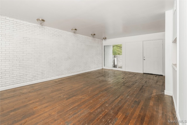 unfurnished room with dark hardwood / wood-style flooring and brick wall