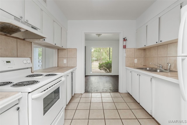 kitchen featuring sink, electric range, decorative backsplash, light tile patterned floors, and white cabinetry