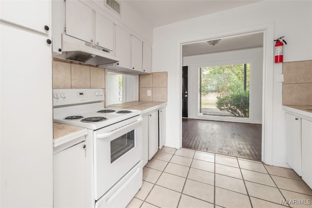 kitchen with light wood-type flooring, backsplash, white cabinetry, and electric stove