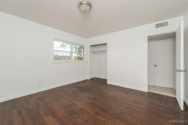 unfurnished bedroom with a closet and dark wood-type flooring