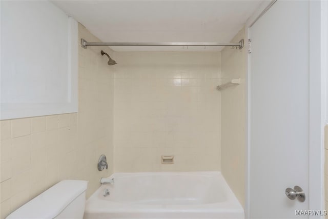 bathroom with toilet, tile walls, and tiled shower / bath