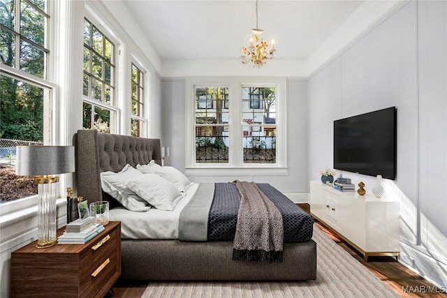 bedroom featuring multiple windows, hardwood / wood-style floors, and an inviting chandelier