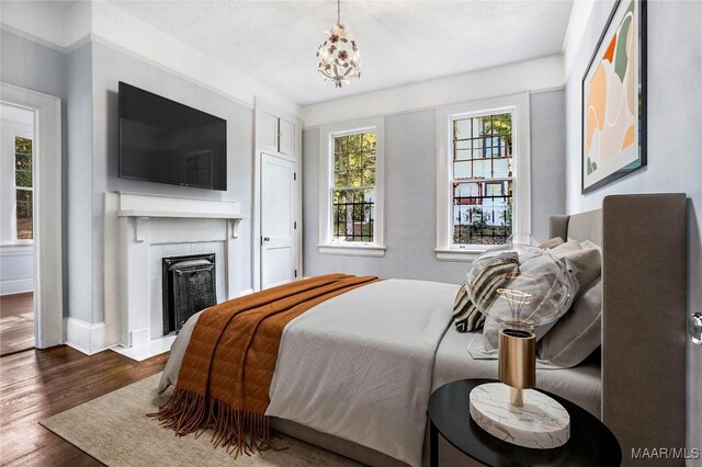 1427 S Court St, Montgomery, AL 36104 - bedroom featuring a tiled fireplace, dark wood-type flooring, baseboards, and a chandelier