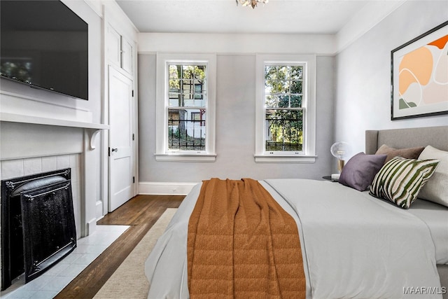 bedroom with light wood-type flooring and a tiled fireplace